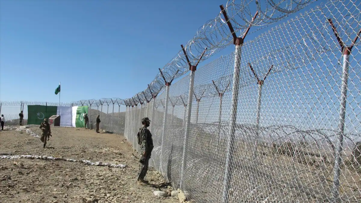 A Pakistani soldier standing alert on fenced border.