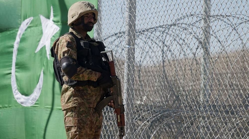 A solider is standing near loc holding his riffle