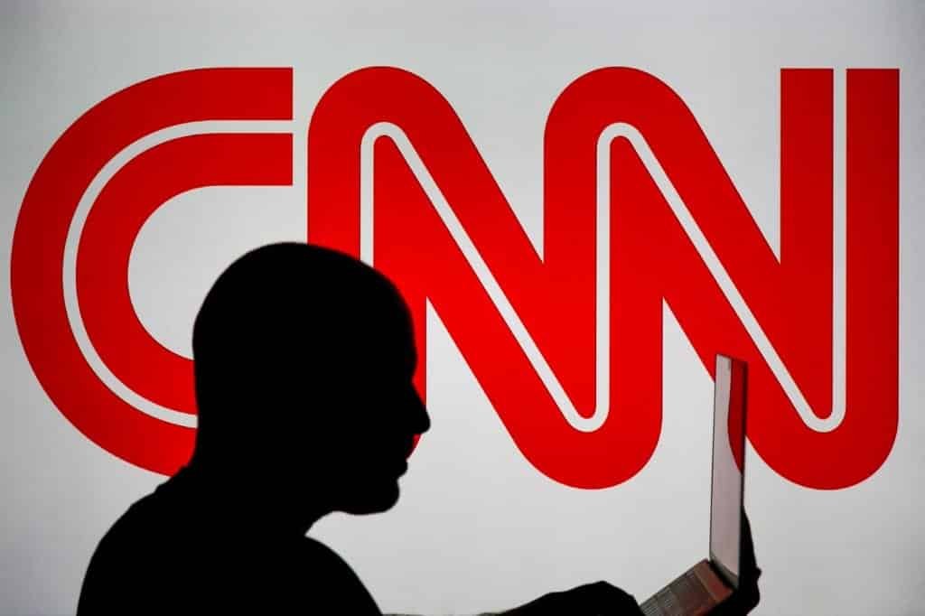 cnn logo with a man using laptop in front of that