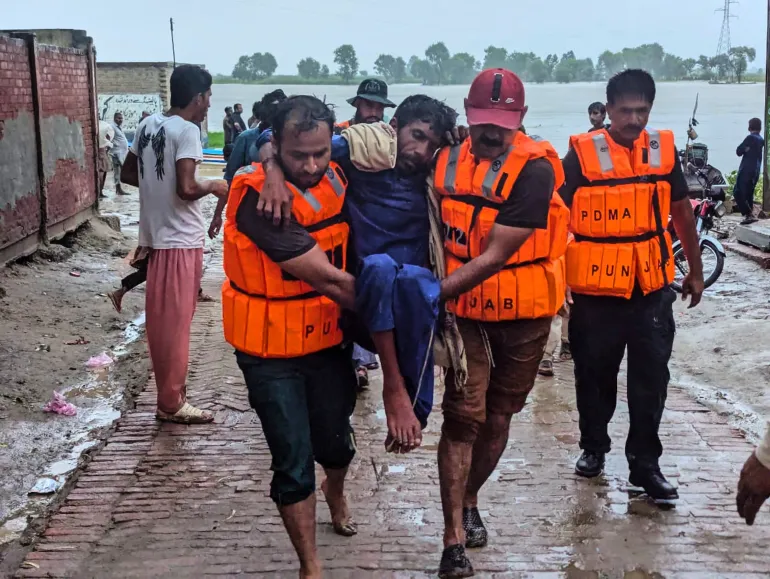 In this photo released by Pakistan’s National Disaster Management Authority, rescue workers help a villager after evacuating him