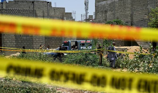 Residents gather as police personnel inspect a site cordoned off with barricade tapes after an alleged drone was shot down in Karachi on May 8, 2025